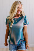 Woman wearing a striped shirt and denim shorts against a plain background