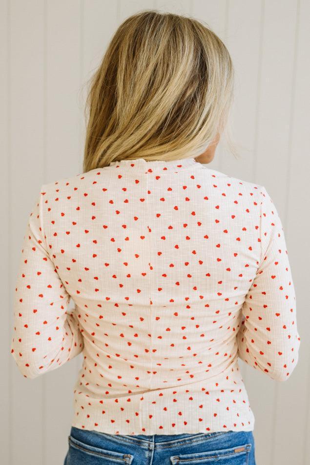 Person wearing a polka dot long-sleeve top with a neutral background