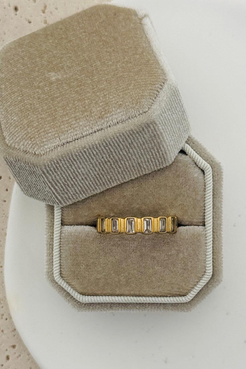 Gold ring with cubic zirconia baguettes all the way around.