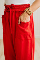 Red pants with a pocket and a white top, on a neutral background