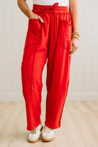 Person wearing red pants with pockets on a light wooden floor.