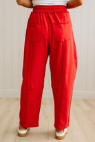 Red pants worn by a person on a light wooden floor with a white wall background