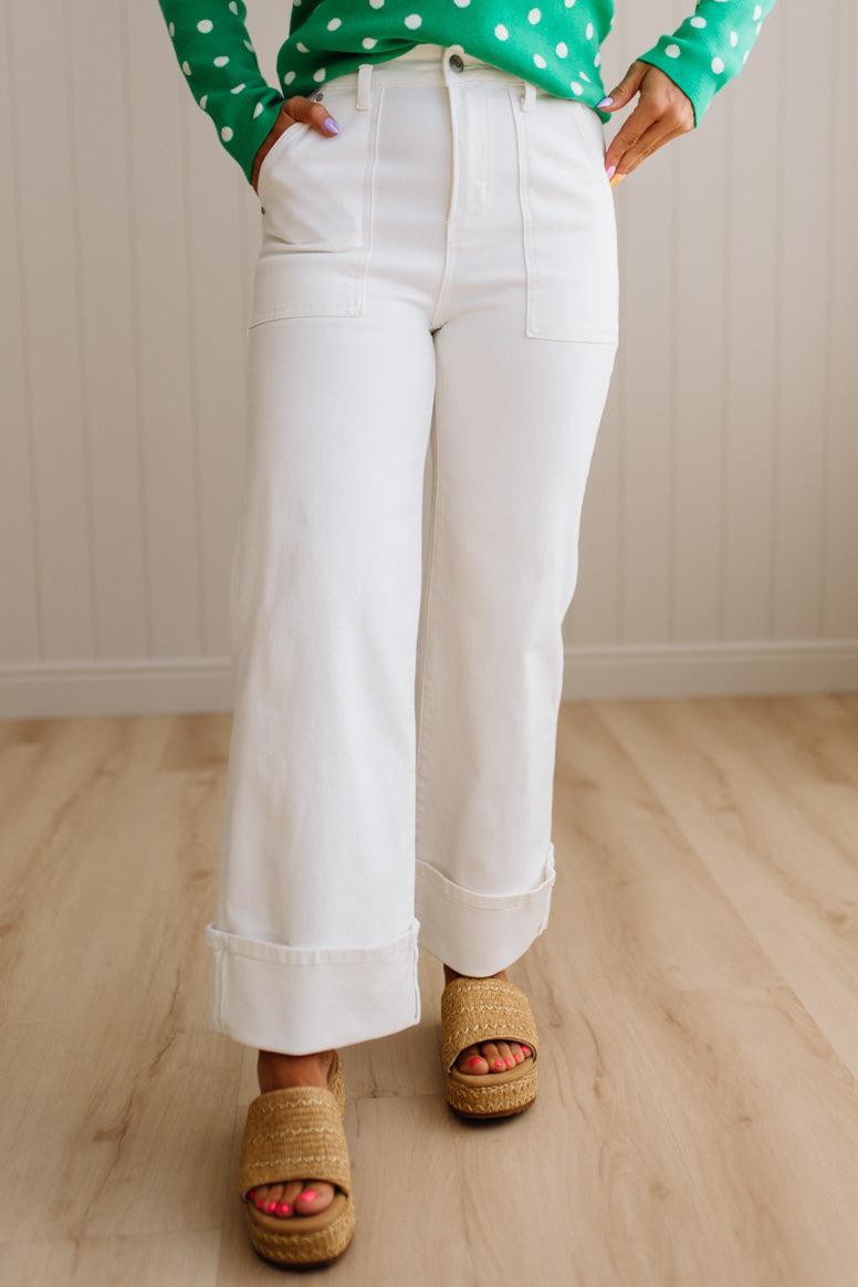 Woman wearing white jeans with square patch pockets and wide cuff at ankle.
