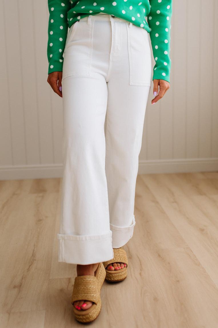 Woman wearing white jeans with square patch pockets and wide cuff at ankle.