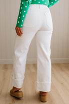 Woman wearing white jeans with square patch pockets and wide cuff at ankle.