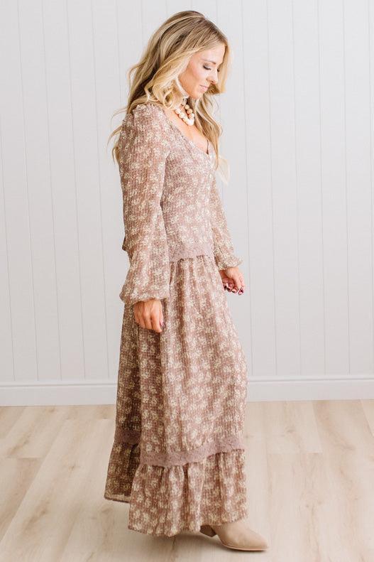Latte brown colored Floral Drop Waist Maxi Dress on a blonde woman with a large white beaded necklace.