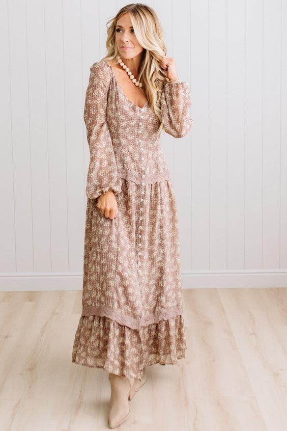 Latte brown colored Floral Drop Waist Maxi Dress on a blonde woman with a large white beaded necklace.