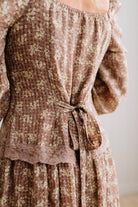Latte brown colored Floral Drop Waist Maxi Dress on a blonde woman with a large white beaded necklace.