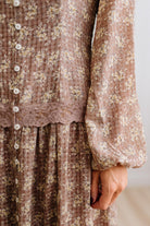 Latte brown colored Floral Drop Waist Maxi Dress on a blonde woman with a large white beaded necklace.