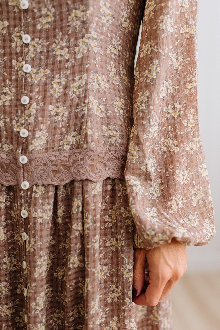Latte brown colored Floral Drop Waist Maxi Dress on a blonde woman with a large white beaded necklace.