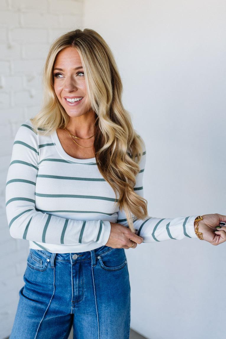 Woman wearing a striped shirt and jeans against a plain background