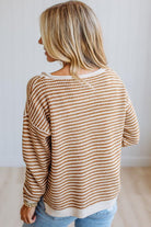 A woman shown from the back wearing a waffle-knit long-sleeve sweater with horizontal brown and cream stripes, paired with light blue jeans.