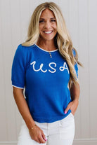 Woman wearing a blue sweater with 'USA' text against a neutral background