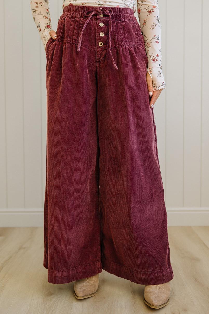 Person wearing maroon wide-leg pants with a light-colored background