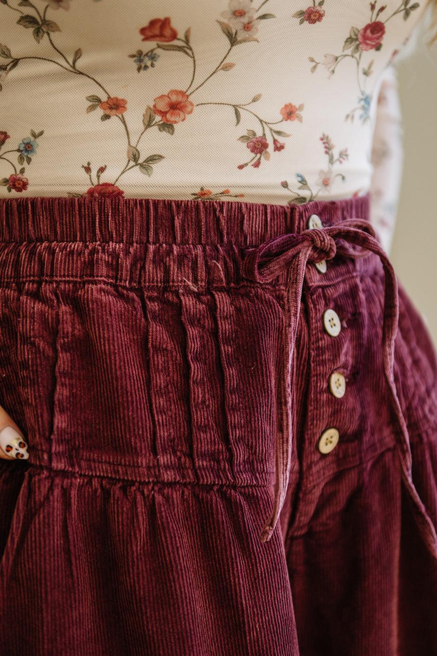 Close-up of a burgundy corduroy skirt with floral top