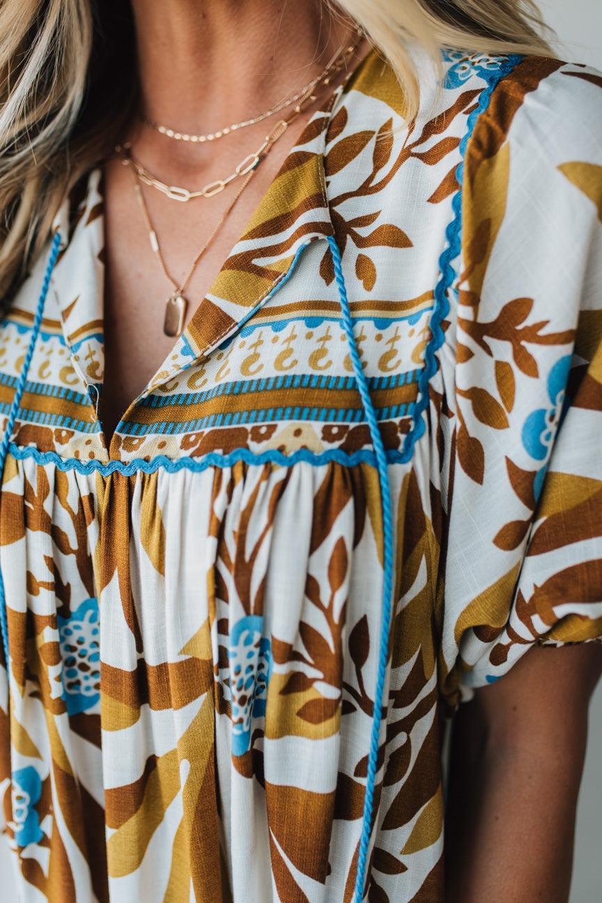 Woman wearing a patterned dress with a neutral background