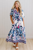 Blonde woman wearing a long printed maxi dress in blue and white with hot pink accents.