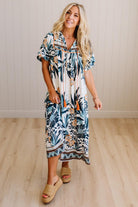 Woman wearing a floral dress standing on a wooden floor with a neutral wall background