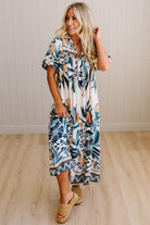 Woman wearing a tropical patterned dress standing on a wooden floor.