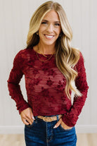 Blonde Woman Wearing A Floral Embroidered Stretch Lace Long Sleeve Top with Dark Jeans and Light Brown Belt.