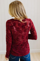 Blonde Woman Wearing A Floral Embroidered Stretch Lace Long Sleeve Top with Dark Jeans and Light Brown Belt.