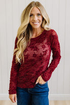 Blonde Woman Wearing A Floral Embroidered Stretch Lace Long Sleeve Top with Dark Jeans and Light Brown Belt.