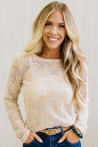 Blonde Woman Wearing A Floral Embroidered Stretch Lace Long Sleeve Top with Dark Jeans and Light Brown Belt.