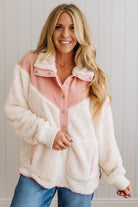 Woman wearing a pink and white sherpa jacket against a light background