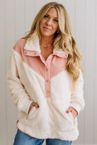 Woman wearing a white and pink fleece jacket against a light background