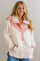 Woman wearing a pink and white fleece jacket against a light background