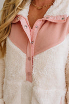 Close-up of a person wearing a pink and white fleece jacket with a gold necklace.