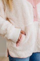 Close-up of a person wearing a fluffy white jacket with pink trim.