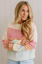Woman wearing a colorful patterned sweater against a plain background