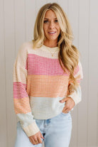 Woman wearing a colorful striped sweater against a neutral background