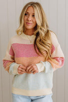 Woman wearing a colorful patterned sweater against a neutral background