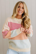 Woman wearing a colorful patterned sweater against a neutral background
