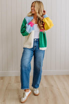Woman wearing a colorful sweater and blue jeans indoors.