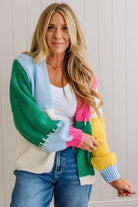 Woman wearing a colorful cardigan with a white wall background