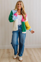 Woman wearing a colorful cardigan with a white wall background