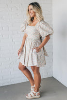 Blonde woman wearing a floral dress with puff sleeves and a large statement bow at the back.