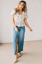 Blonde woman wearing a floral print tie front shirred hem blouse top with puff sleeve.