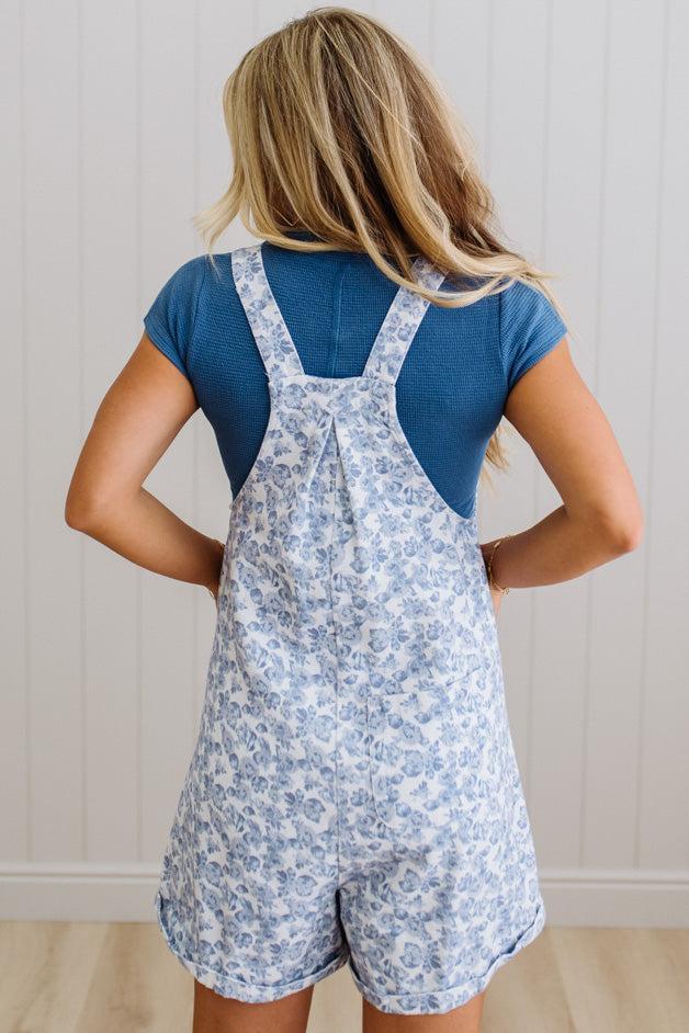 Woman wearing a blue floral romper with a plain background