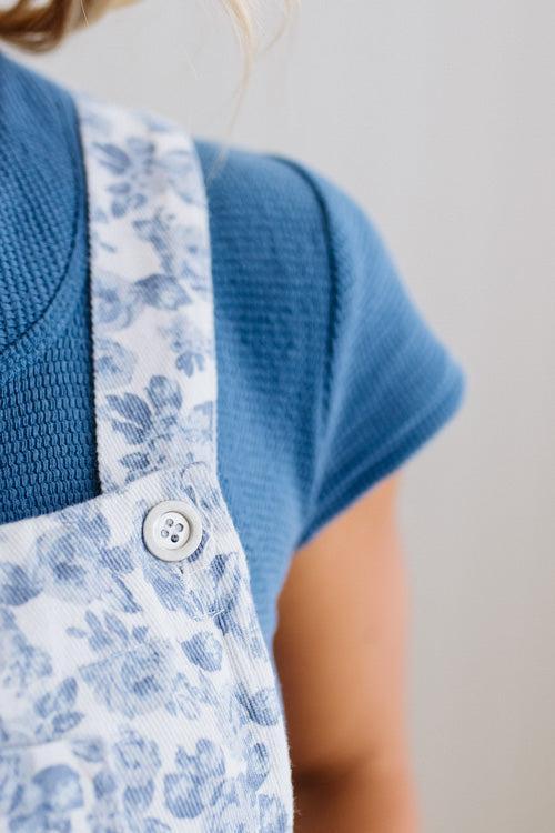 Person wearing a blue floral dress with a plain background
