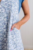 Person wearing a blue floral dress with a plain background