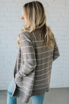 Woman wearing a striped sweater against a white brick wall.