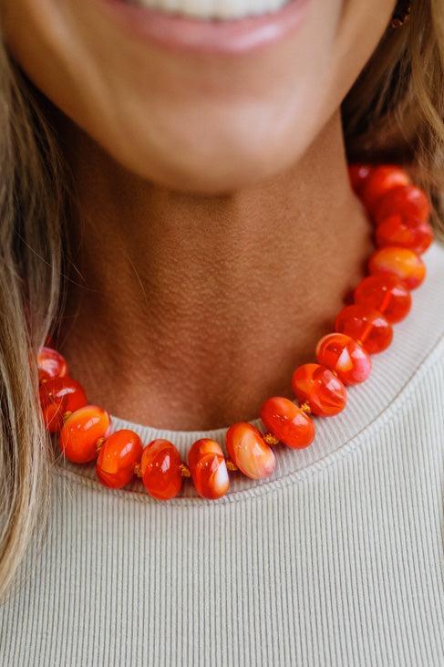 Colorful Bead Necklace in bright orange on a woman's neckline.