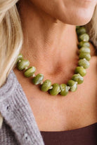 A CHUNKY BEADED NECKLACE WITH KNOTS BETWEEN EACH BEAD IN A GREEN MARBLED TONE.