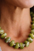 A CHUNKY BEADED NECKLACE WITH KNOTS BETWEEN EACH BEAD IN A GREEN MARBLED TONE.