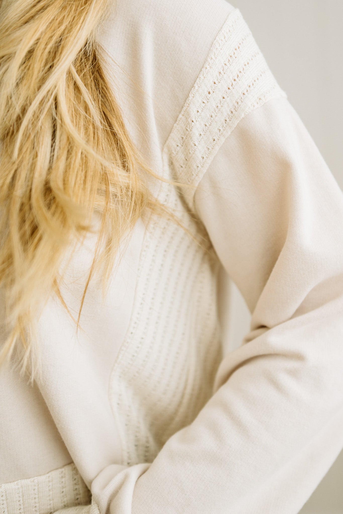 Close-up of a person wearing a beige sweater with a blurred background