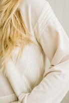 Close-up of a person wearing a beige sweater with a blurred background